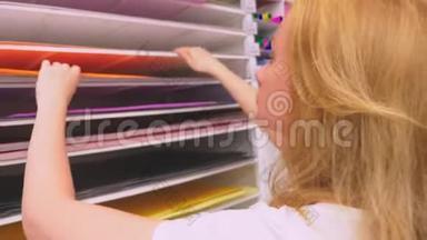 五颜六色的艺术品在一个<strong>文具店</strong>里出售。 女人在商<strong>店</strong>里选择一张彩色纸。